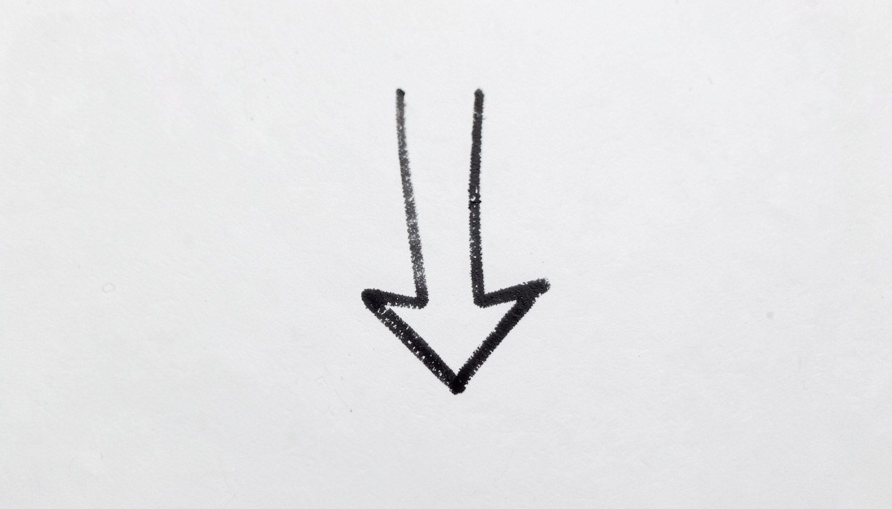 Small hand-drawn arrow doodle pointing downward